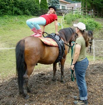 Kind macht Brücke auf Pferd